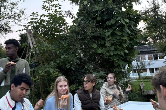 Die Teilnehmenden essen Pizza im Garten des Nordkollegs in Rendsburg.